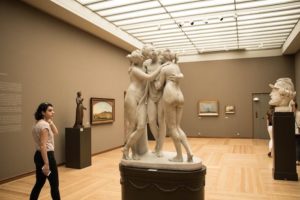 vue générale d'un visiteur admirant des statues antiques dans une salle d'exposition d'un musée